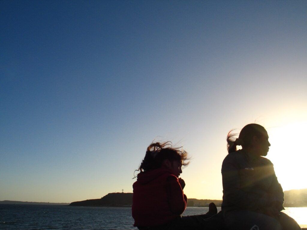 Dos mujeres miran el mar al atardecer